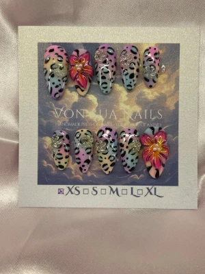 SugarSafari(XS);Medium Almond - Unika handgjorda press-on naglar i en medium lång mandelform med leopardmönster i pastellfärger som rosa, blått,lila,gult och oranget. Två naglar har handgjorda 3D-blommor i rosa och gult, och flera naglar är dekorerade med små glittriga blommor detaljer. Perfekt för dig som vill sticka ut med färg och mönster.XS: 14 mm, 11 mm, 11,5 mm, 10 mm, 8 mm
