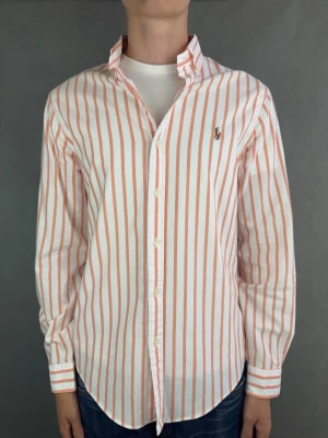 Ralph Lauren skjorta - Ralph Lauren Skjorta Märke: Polo Ralph Lauren Storlek: M Passform: Slimfit Färg: Korall / vit randig Skick: Mycket bra Beskrivning: utan defekter. Modellen på bilden: 183 cm / 74 kg