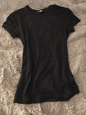 Svart basic t-shirt i bomull - En enkel svart t-shirt med rund hals och korta ärmar. Tillverkad i mjuk bomull som känns skön mot huden. Perfekt att matcha med jeans eller shorts för en clean och stilren look.
