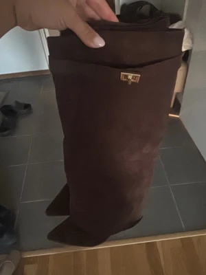 Bruna mocka stövlar/klackar  - Säljer ett par bruna overknee stövlar med spetsig tå och guldfärgad detalj upptill. Stl 38, använd 2-3 gånger 