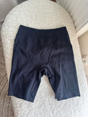 Svarta cykelshorts från Relode Prime Scrunch - Säljer ett par svarta cykelshorts från Relode med hög midja och ribbad linning. Shortsen är tillverkade i ett stretchigt material som passar perfekt för träning eller en aktiv vardag. Enkel och stilren design utan synliga detaljer.