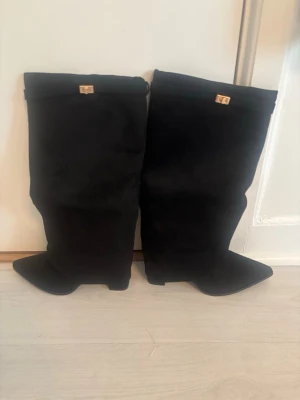 Svarta overknee stövlar från Eytys - Säljer ett par svarta overknee stövlar från Eytys i mjukt mockaliknande material. Stövlarna har spetsig tå och en liten gulddetalj upptill. Perfekta för att lyfta vilken outfit som helst.