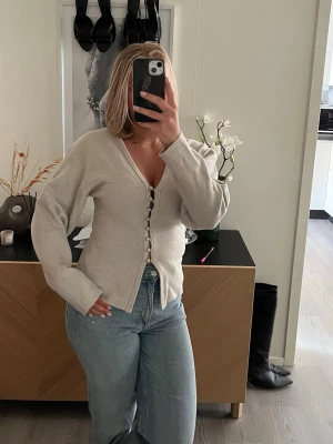 Beige kofta med knappar - Populär figursydd cardigan från Gina Tricot i en fin beige nyans. Modellen framhäver midjan och har dekorativa knappar framtill som ger ett stilrent och feminint uttryck. Perfekt att bära både till jeans, kostymbyxor eller kjol.  ✨ Figursydd passform ✨ Snygga knäppningsdetaljer framtill ✨ Mjuk och bekväm kvalitet ✨ Trendig och lättstylad ✨ Storlek S ✨ Fint skick 