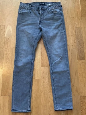 Grå slim fit jeans från Weekday - Snygga grå slim fit jeans från Weekday med klassisk femficksdesign och raka ben. Jeansen har en diskret tvättad look och är tillverkade i mjuk bomullsdenim med lite stretch för extra komfort. Perfekta för en avslappnad och trendig stil.
