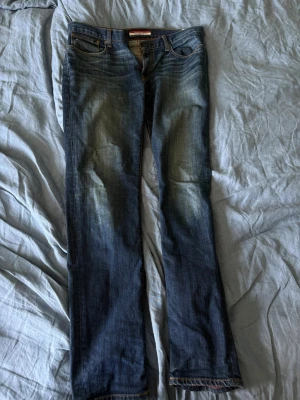 Slim fit jeans i blå denim - Slim fit jeans i klassisk blå denim med snygga slitningar på låren och raka ben. Jeansen har fem fickor och kontrastsömmar. Perfekta för en avslappnad och trendig look.