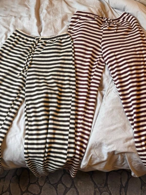Randiga stickade loungewearbyxor -H&M  - Två par stickade loungewearbyxor med horisontella ränder. Ena paret är svart och vitt, det andra är vinrött och vitt. Båda har dragsko i midjan och mjuk, avslappnad passform. Perfekta för hemmamys och chill dagar.
