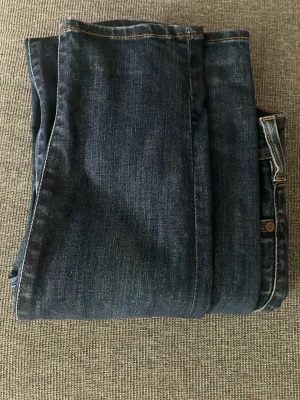 Mörkblå raka jeans - Snygga mörkblå jeans med raka ben och klassisk femficksmodell. Jeansen har kontrastsömmar och en diskret tvättad look. Tillverkade i slitstarkt denimtyg som ger en tidlös känsla. Perfekta för dig som gillar enkel och stilren stil.