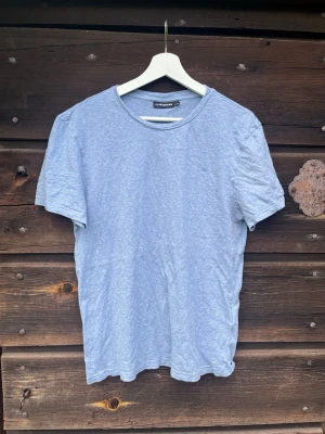 Ljusblå t-shirt från J.Lindeberg - En enkel och stilren ljusblå t-shirt från J.Lindeberg. T-shirten har rund halsringning och korta ärmar. Tillverkad i mjuk bomull som känns skön mot huden. Perfekt basplagg till garderoben.