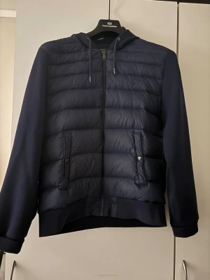 Mörkblå pufferjacka med huva - Säljer en blå Ralph lauren Cardigan, fräscht skick och knappt använd. Perfekt för vår, sommar och höst, Kom gärna med bud. 