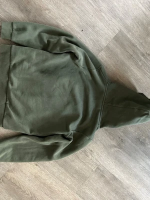 Olivgrön hoodie från Peak Performance - Säljer en olivgrön hoodie från Peak Performance. Hoodien har en klassisk huva och är gjord i mjukt bomullsmaterial. Perfekt för dig som gillar en enkel och stilren look. Inga synliga tryck eller mönster, bara clean och snygg.