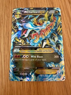Pokémonkort Mega Charizard EX - Säljer ett samlarkort, Mega Charizard EX från Pokémon. Kortet har en färgstark design med blå, svart och gul bakgrund och holografiska effekter. Text och illustrationer är detaljerade och kortet har 230 HP samt attacken Wild Blaze.