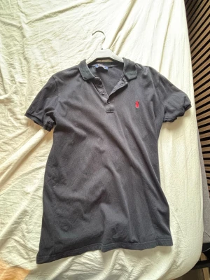 Svart pikétröja från Ralph Lauren - Klassisk svart pikétröja från Ralph Lauren säljs billigt då den varit igenom en del tvättar.