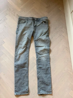 Grå raka jeans från Jacob Cohen - Snygga grå jeans från Jacob Cohen med raka/lite slim ben och klassisk femficksmodell. Jeansen har knäppning framtill och diskret logga på myntfickan. Perfekta för en avslappnad och stilren look. Har en lagning framför knapparna på framsidan