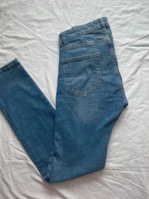 Dressmann jeans  - Säljer ett par ljusblå jeans med hög midja och klassisk femficksdesign. Jeansen har smal passform och är tillverkade i stretchigt denimtyg för extra komfort. Perfekta till en avslappnad look och passar till det mesta i garderoben.