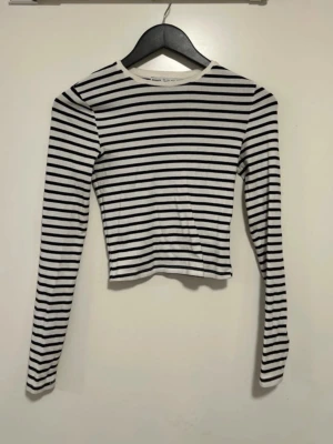 Randig långärmad topp från Bershka - Säljer en svartvit randig långärmad topp från Bershka. Perfekt att styla med jeans eller kjol för en enkel och snygg look. Storlek S. 