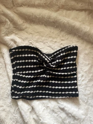 Randig svartvit bandeau tubtopp - Säljer en snygg bandeau tubtopp med svart och vitt randigt mönster från new Yorker. Toppen är axelbandslös och har en twistad detalj framtill. 