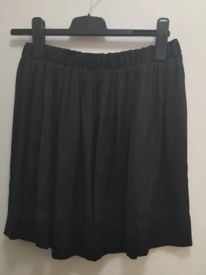 Svart kjol 45cm lång - Säljer en svart kjol med resår i midjan. Märken och storlek står inte, men känns som en S/M. Se bilder för mått. Kjolen har en luftig och flowy känsla, perfekt för att styla med en crop top eller oversized tröja. Materialet känns lätt och bekvämt, mjukt och glansigt tyg, och den svarta färgen gör den enkel att matcha. Kolla gärna mina andra annonser <3.