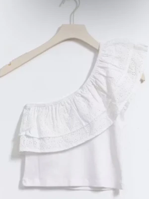 Vit oneshoulder topp med volang - Säljer en vit oneshoulder topp med bred volangkant i broderad spets. Toppen är ärmlös och har en asymmetrisk skärning som ger en trendig look. Perfekt för dig som vill sticka ut lite extra med en feminin och luftig stil.