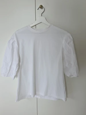 Vit blus med puffärmar - Säljer en enkel och stilren vit blus med puffiga trekvartsärmar. Blusen har rund halsringning och är gjord i mjukt bomullsmaterial. Perfekt för dig som gillar en clean look med lite extra volym på ärmarna.