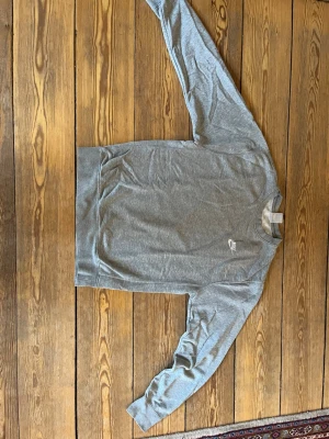Grå sweatshirt från Nike - Klassisk grå sweatshirt från Nike med broderad vit logga på bröstet. Tröjan har rund halsringning, långa ärmar och ribbade muddar vid ärmslut och nederkant. 