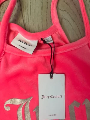 Rosa velourklänning Juicy Couture - Snygg rosa kortklänning från Juicy Couture i mjuk velour med silverfärgad logga framtill. Klänningen har smala axelband. Aldrig använd, i storlek 12-13 år/152-158