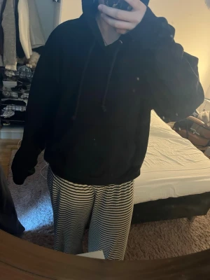 Svart hoodie från Weekday - En klassisk svart hoodie från Weekday i storlek M. Hoodien har en rymlig huva med dragsko och en avslappnad passform. Perfekt för dig som gillar en enkel och stilren look. Materialet känns mjukt och bekvämt mot huden.