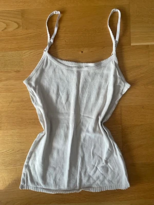Vit linne från Noa Noa - Söt vit linne från Noa Noa i 100% bomull. Toppen har smala axelband, och ribbad midja för en snygg passform. Perfekt till sommaren. Använd sparsamt. Köpt secondhand. Fint skick. 