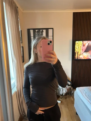 Mörkgrå långärmad topp med öppen rygg - Säljer en mörkgrå långärmad topp med öppen rygg från Gina Tricot i storlek S och använd fåtal gånger 