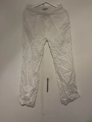 Vita linnebyxor från H&M - Säljer ett par vita linnebyxor från GinaTricot med rak passform och klassisk midja. Byxorna har dragkedja och knapp framtill samt fickor i sidorna. Perfekta för en avslappnad och stilren look under varma dagar.