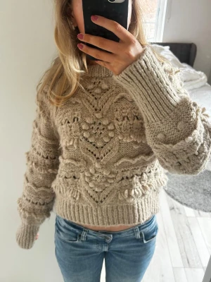Beige stickad tröja Zara - Säljer en beige stickad tröja från Zara som inte säljs längre, med mönster och strukturstickade detaljer. Tröjan har rund hals, långa ärmar och breda ribbade muddar. Det är inte stickig alls, har väldigt mjuk och skönt material.😊