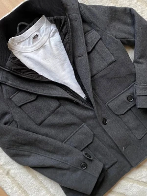 Fieldjacket - Snygg fieldjacket i grå färg. Stilren och perfekt nu när det börjar bli lite varmare☀️.                                  Storleken är L. 🚨Vid frågor kontakta mig🤗