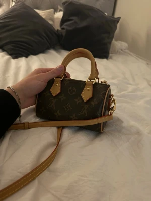 Louis Vuitton monogram handväska - Klassisk brun handväska från Louis Vuitton med ikoniskt monogrammönster och detaljer i ljusbrunt skinn. Väskan har både handtag och axelrem samt dragkedja upptill. Perfekt för dig som gillar tidlös design och lyxiga accessoarer. Box och dustbag medföljer. Som ny! Öppen för prisförslag!