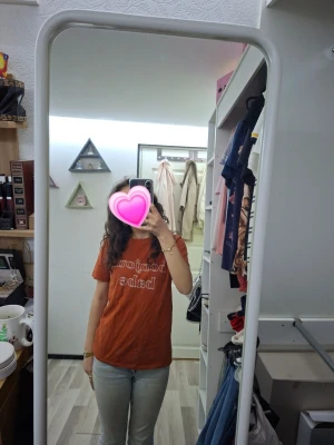 Rustbrun t-shirt med tryck - Säljer en rustbrun t-shirt med texten 'Bonjour Babe' i vitt framtill. T-shirten har klassisk passform, rund halsringning och korta ärmar. Perfekt för dig som gillar en enkel men trendig look. Typ alldrig använd.