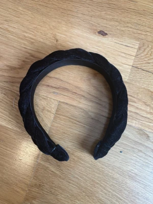 Svart flätat sammetsdiadem - Snyggt svart diadem med flätad design i mjuk sammet. Perfekt accessoar för att lyfta din look med en trendig touch. Diademet har en klassisk form och är bekvämt att bära hela dagen.