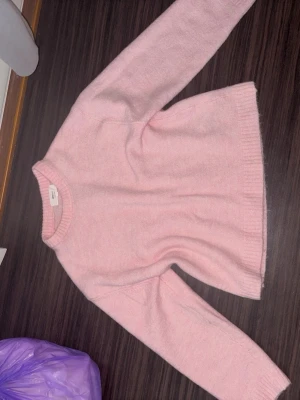 Ljusrosa stickad tröja Gina Tricot - Supersöt ljusrosa stickad tröja från Gina Tricot i mjuk ullblandning. Tröjan har rund halsringning, långa ärmar och ribbade muddar vid hals, ärmslut och nederkant. Perfekt för mysiga dagar och enkel att styla med jeans eller kjol.