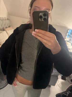 Svart teddyjacka från Jacqueline de Yong - Mysig svart teddyjacka med huva från Jacqueline de Yong. Jackan har dragkedja framtill och är fodrad med ett diskret mönstrat tyg. Perfekt för kyliga dagar när du vill vara både varm och snygg. Står L men den är väldigt liten i storleken. Skulle säga S/XS. 
