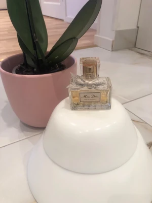 Miss Dior Eau de Parfum 50ml - Miss Dior Eau de Parfum från Dior i en elegant glasflaska med guldfärgad spray och en dekorativ silverfärgad rosett. Flaskan har en klassisk rektangulär form och etikett framtill. Doften är feminin och tidlös. Hälften av innehållet är kvar alltså 15mm av totalt 30mm😊