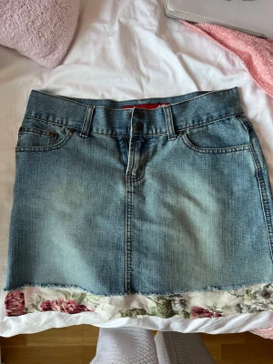 Blå jeanskjol med blommig kant storlek M - Säljer en blå jeanskjol vintage i super bra skick!! Storlek M🩷 för att se måtten på midjan gå till sista bilden 😌