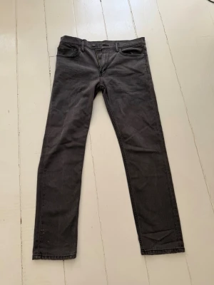 Svarta skinny jeans från Levi's - Säljer ett par svarta skinny jeans från Levi's med klassisk femficksdesign och dragkedjegylf. Jeansen har en smal passform och är tillverkade i ett mjukt denimtyg. Tyget är rätt så slitet och det är lite missfärgat efter många tvättningar. Men annars inga slitningar i materialet eller heelbite. W34 L34 Längd: 102cm