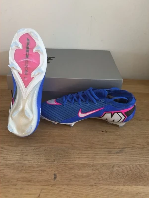ZM VAPOR 16 ELITE FG - Sprillans Nya direkt från boxen. Skorna har en strömlinjeformad design, snörning och en yttersula med dobbar för bra grepp på planen. Tillverkade i syntetmaterial för lätt vikt och bra bollkontroll. Perfekta för dig som vill sticka ut på planen. Nypris om man skulle köpa online: 2200kr, mitt pris: 749kr, exakt samma nya skor fast väldigt mycket mindre pris!