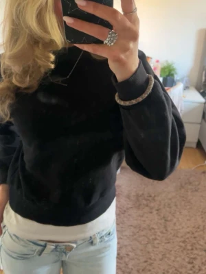 Svart oversized sweatshirt - Mjuk svart sweatshirt med avslappnad, oversized passform och rund hals. Tröjan har långa ärmar och ribbade muddar vid ärmslut och nederkant. Perfekt att styla med jeans för en chill look. Materialet ser ut att vara bomull eller bomullsblandning.