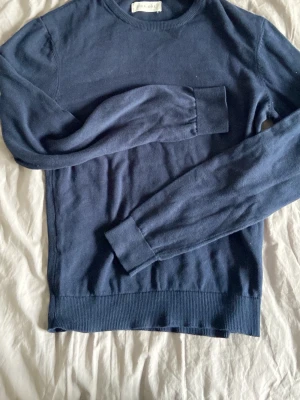 Mörkblå tröja från Pier One - Mörkblå långärmad tröja från Pier One med rund halsringning och ribbade muddar vid ärmslut och nederkant. Enkel och stilren design som passar perfekt till jeans eller chinos. Mjuk och bekväm bomullskänsla.