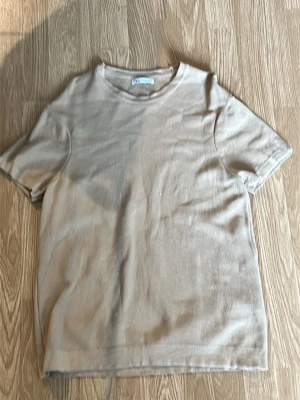 Beige kortärmad t-shirt i bomull - En enkel och stilren beige t-shirt med korta ärmar. Tillverkad i mjuk bomull för en skön känsla och avslappnad passform. Perfekt basplagg att matcha med allt i garderoben.