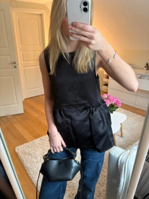 Svart ärmlös peplumblus från NA-KD - Säljer en svart ärmlös peplumblus från NA-KD med rund halsringning och voluminös nedre del. Storlek 34. Helt ny med prislapp, säljer då den inte har använts 🌟 Passar perfekt till både fest eller vardags. Pris kan diskuteras vid snabbt köp♥️