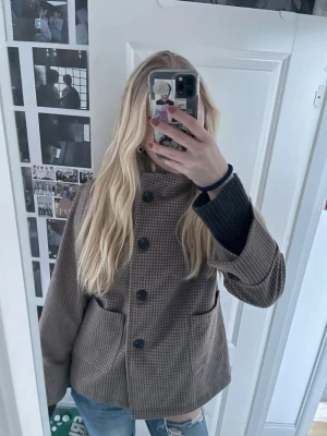 Brun jacka/kappa med knappar - Jacka i brunt rutmönster med stora svarta knappar framtill och två fickor. Gammal modell på jackan och finns inget märke. Priset kan diskuteras, skriv för fler bilder🥰