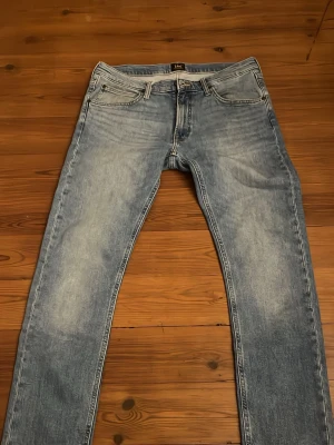 Ljusblå raka jeans från Lee - Säljer ett par ljusblå jeans från Lee med klassisk femficksmodell och raka ben. Jeansen har en snygg tvättad look och är tillverkade i denim. Perfekta för en avslappnad stil och passar till det mesta.