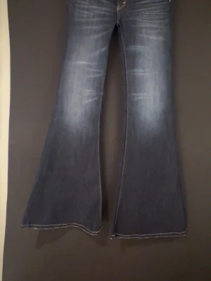 Mörkblå utsvängda jeans - Säljer ett par mörkblå jeans med tydlig utsvängd passform och snygga slitningar framtill. Jeansen har klassisk femficksdesign och är perfekta för dig som gillar retrostil och vill sticka ut med en cool siluett. Säljer dessa jättefina jeans ifrån cheap monday, har aldrig använt dom men råkade ta av lappen så därav inte kunde skicka tillbaka. Storlek 27/32       Färgen: star blue