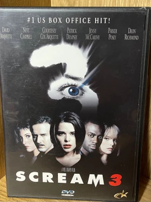 Scream 3 DVD-film - Säljer en DVD med filmen Scream 3, en skräckthriller från 2000. Omslaget är svart med ikonisk mask och blått öga, och innehåller bonusmaterial som trailer, musikvideo och borttagna scener. Perfekt för dig som gillar spänning och klassiska skräckfilmer.