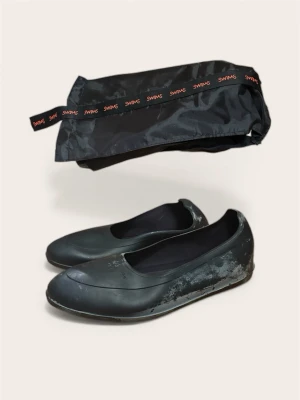 Swims Galoscher inkl. förvaringspåse – Strl L - Säljer ett par svarta klassiska galoscher från Swims, kompletta med tillhörande förvaringspåse. Träs enkelt utanpå dina läderskor/finskor för att skydda mot regn och slask utan att förstöra stilen. Storlek L (motsvarar ca skostorlek 43–44,5).  Skick: Sparsamt använda och i princip som nya. Gummit är helt och intakt utan skador. Kommer från ett rök- och djurfritt hem.  Pris: 399 kr.  Finns att hämta i Bromma.