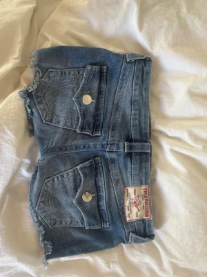 Blå jeansshorts från True Religion - Snygga blå jeansshorts från True Religion med jättelång midja , perfekta till sommaren köpta för 1100 typ och säljer för 550 trots aldrig andvända bara testade , pris går att diskutera , st 26 så runt xs-s men passar de mesta runt de storlekarna då de e stretchiga 